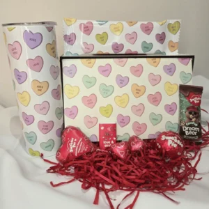 Valentine’s themed sweet gift box with chocolates, heart-shaped sweets, tumbler, and festive red filler